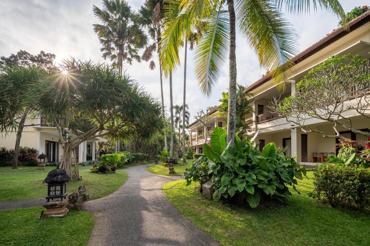 a walkway through the courtyard of a resort with palm trees at Pertiwi Resort & Spa in Ubud