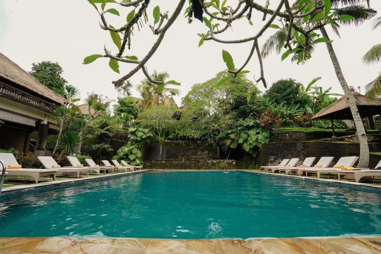 a swimming pool in a resort with lounge chairs at Pertiwi Resort & Spa in Ubud