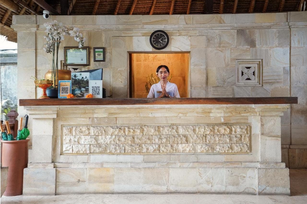 a woman standing behind a counter in a stone building at Pertiwi Resort & Spa in Ubud