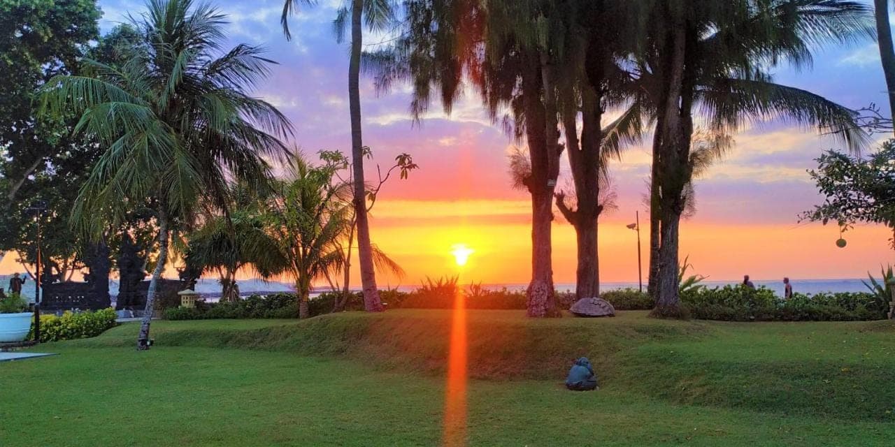 a person sitting in a park watching the sunset at The Patra Bali Resort & Villas - CHSE Certified in Kuta