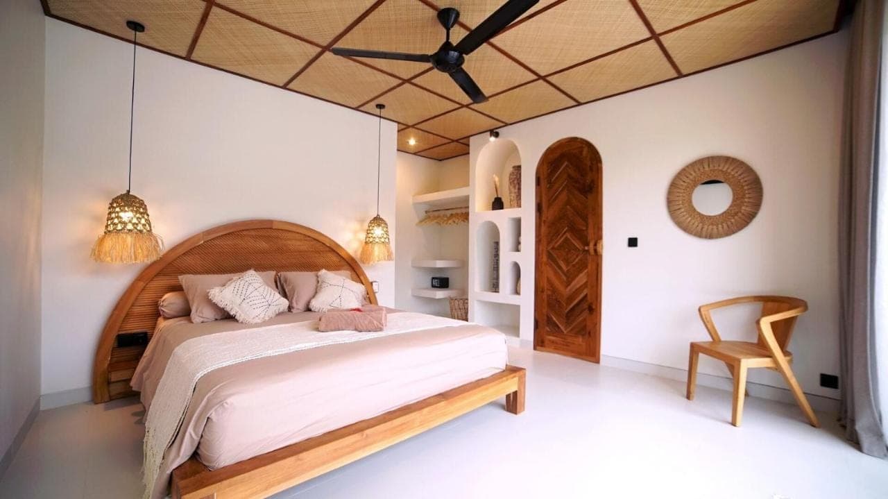 a bedroom with a large bed and a chair at Villa Naga\u00efa - Private Pool, Rooftop & Agung Views in Amed