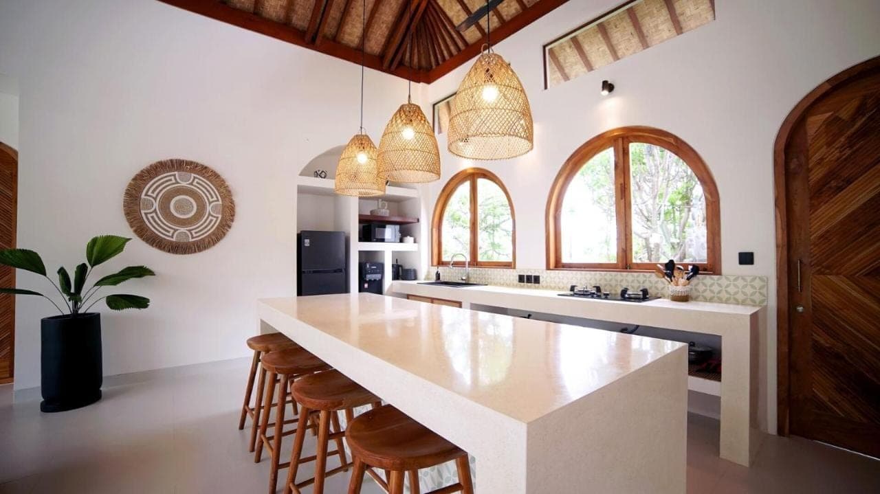 a kitchen with a large white island with bar stools at Villa Naga\u00efa - Private Pool, Rooftop & Agung Views in Amed