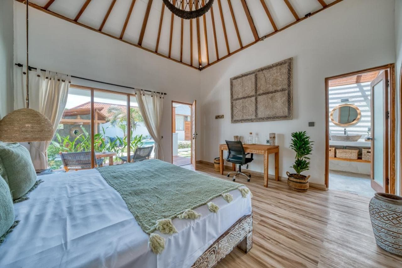 a bedroom with a large bed and a desk at Noho Stay Bali in Uluwatu