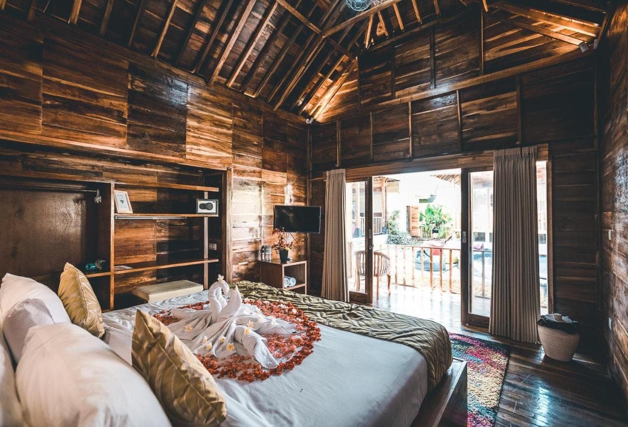 a bedroom with a bed in a room with wooden walls at Ocho Bali Surf Camp in Uluwatu