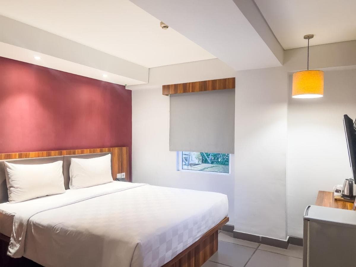 a bedroom with a white bed and a red wall at Swiss-Belexpress Kuta Legian in Kuta