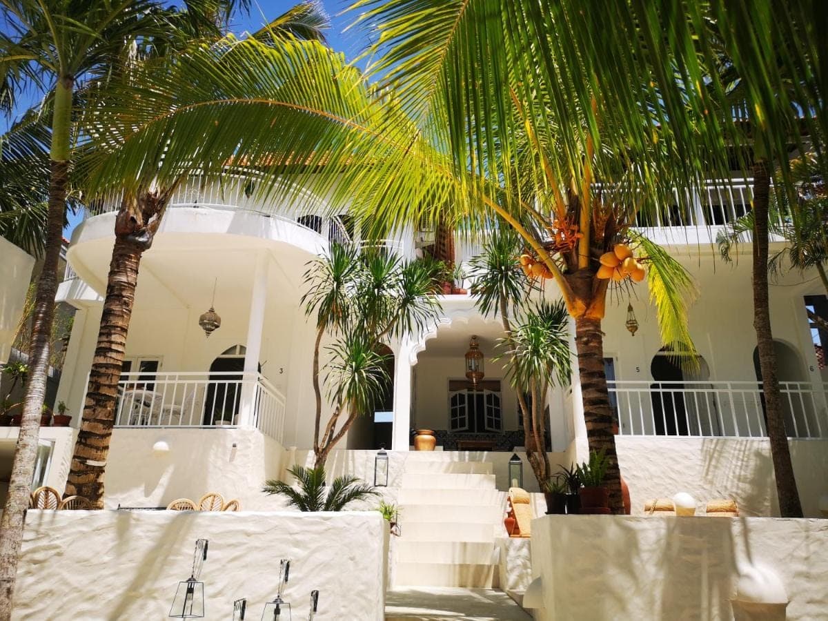 a white house with palm trees in front of it at Segredo Uluwatu in Uluwatu