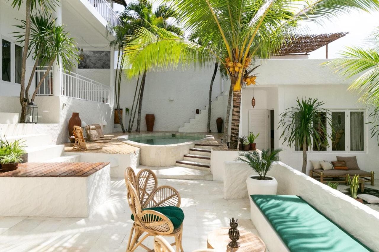 an outdoor patio with a pool and palm trees at Segredo Uluwatu in Uluwatu