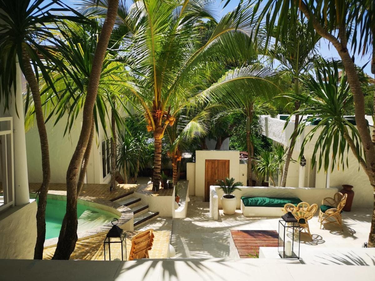 a living room with palm trees and a pool at Segredo Uluwatu in Uluwatu