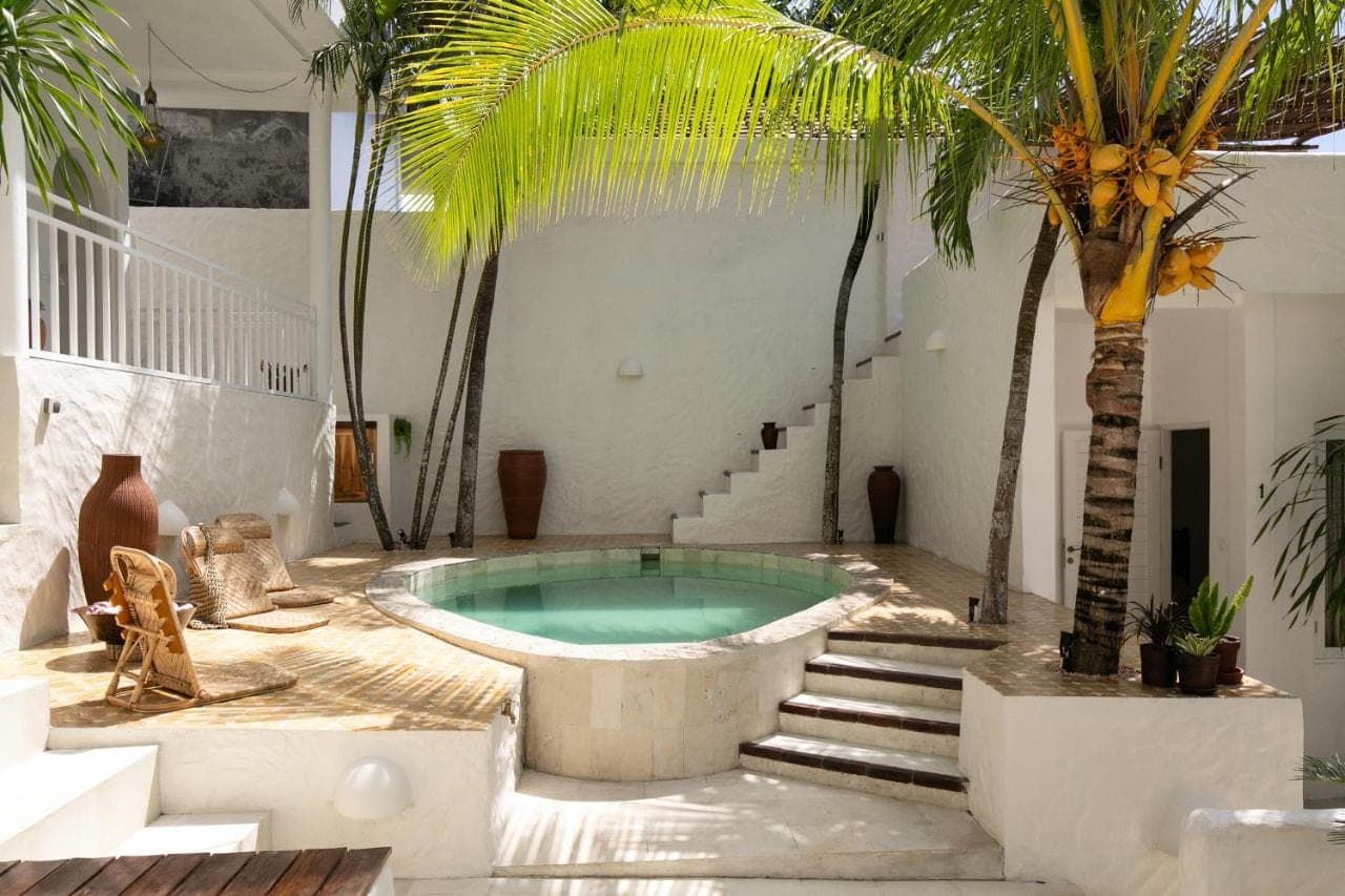 a pool in a courtyard with palm trees and stairs at Segredo Uluwatu in Uluwatu