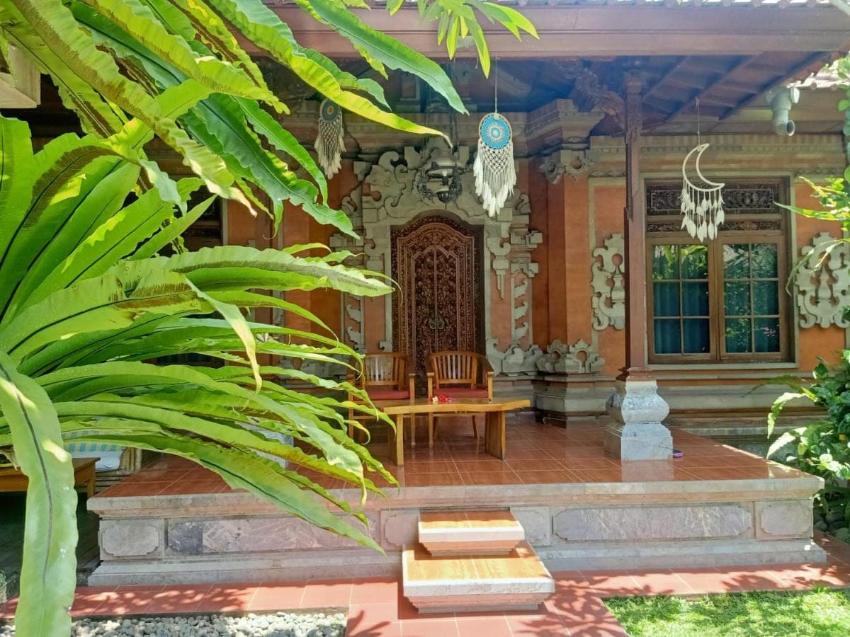 a porch of a house with a bench and plants at Ngetis Home Stay in Sanur