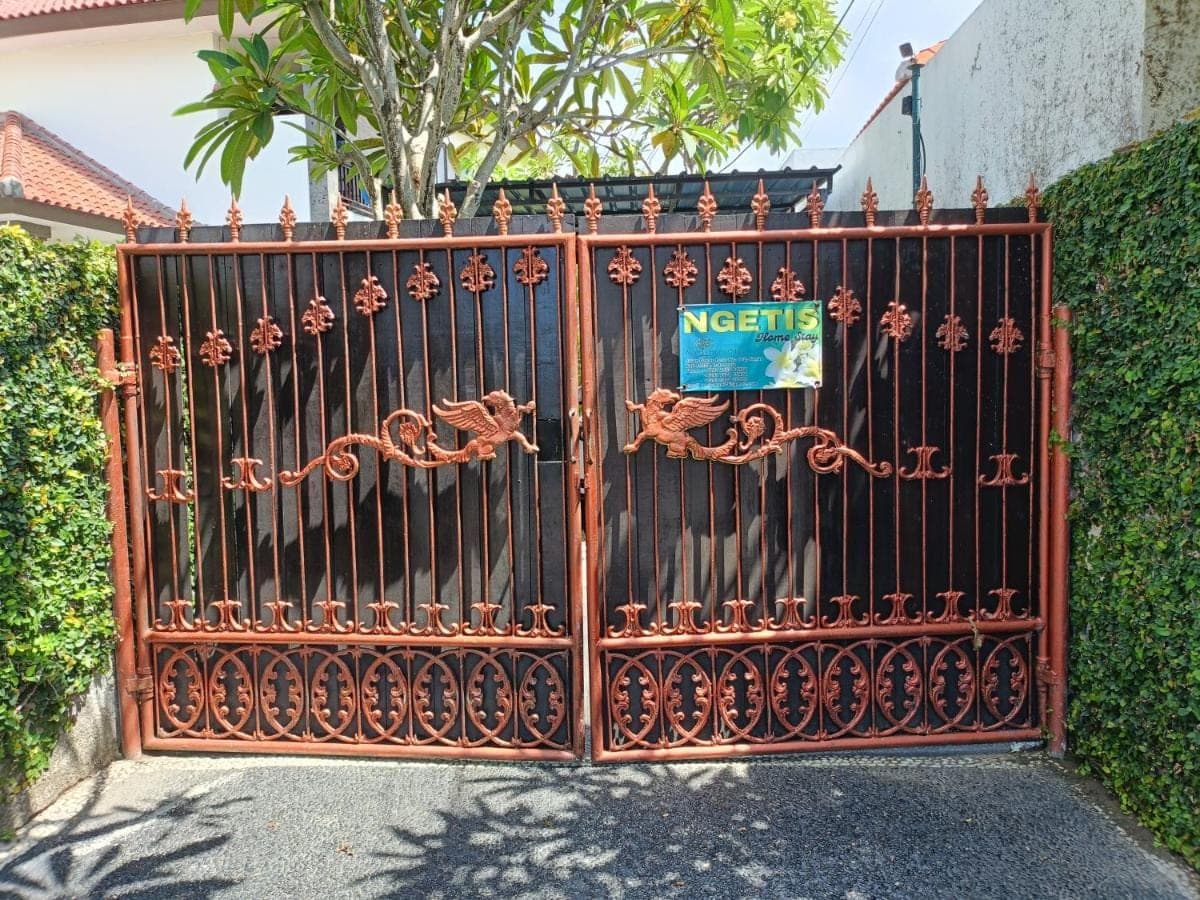 an iron gate with a sign on it at Ngetis Home Stay in Sanur