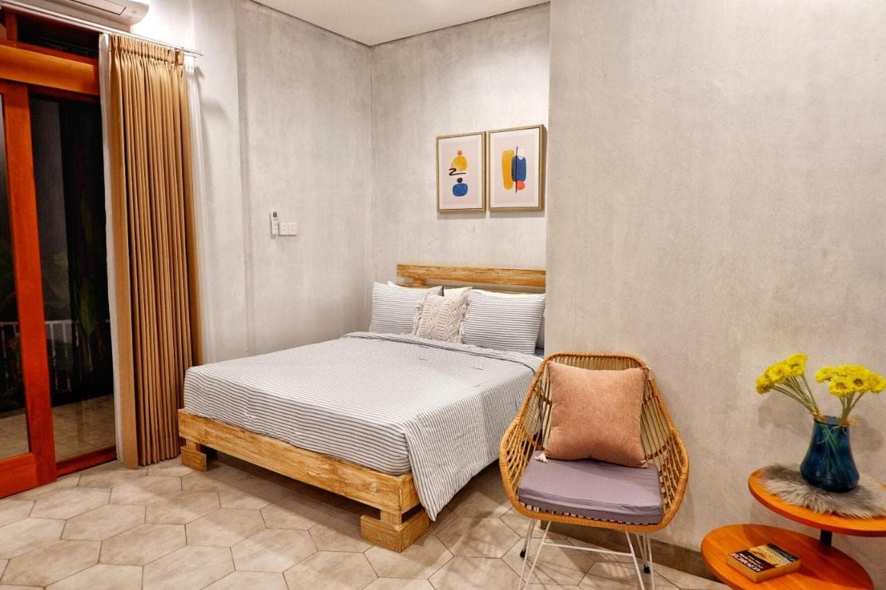 a bedroom with a bed and a chair at The Sloth Bali in Canggu