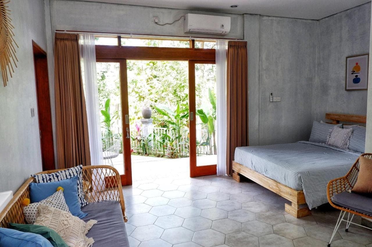 a bedroom with a bed and a sliding glass door at The Sloth Bali in Canggu