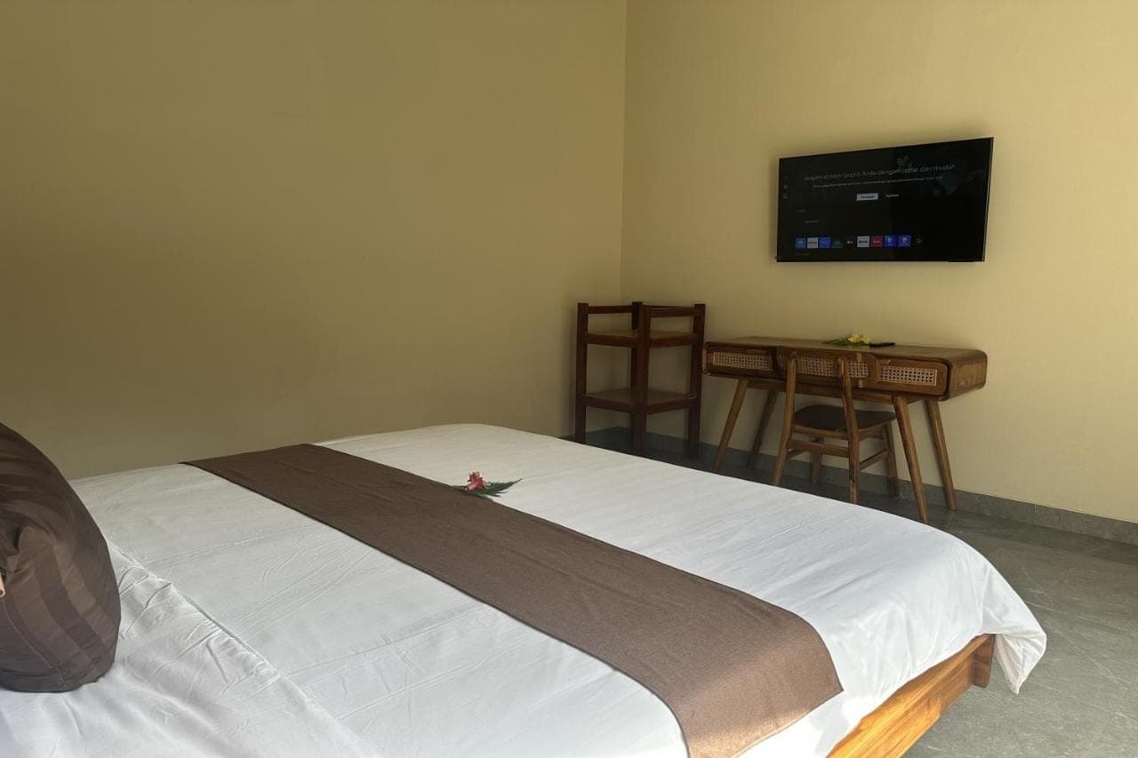 a bedroom with a bed and a table and a flat screen tv at Nawan Nusa Dua Bali in Nusa Dua