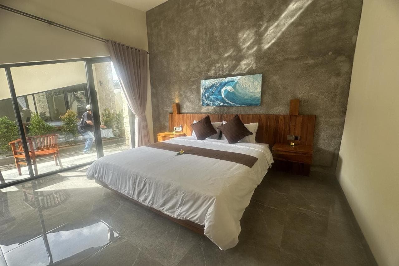 a bedroom with a large bed and a large window at Nawan Nusa Dua Bali in Nusa Dua