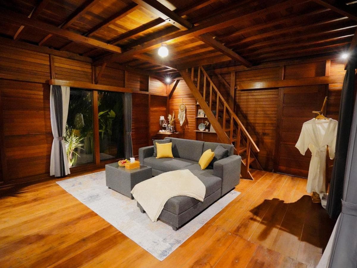 a living room with a couch and a staircase at Romantic Wooden House with Private Pool in Ubud - Raka d'Uma in Ubud