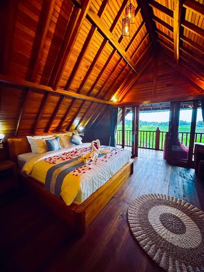 a bedroom with a large bed in a room with windows at Romantic Wooden House with Private Pool in Ubud - Raka d'Uma in Ubud