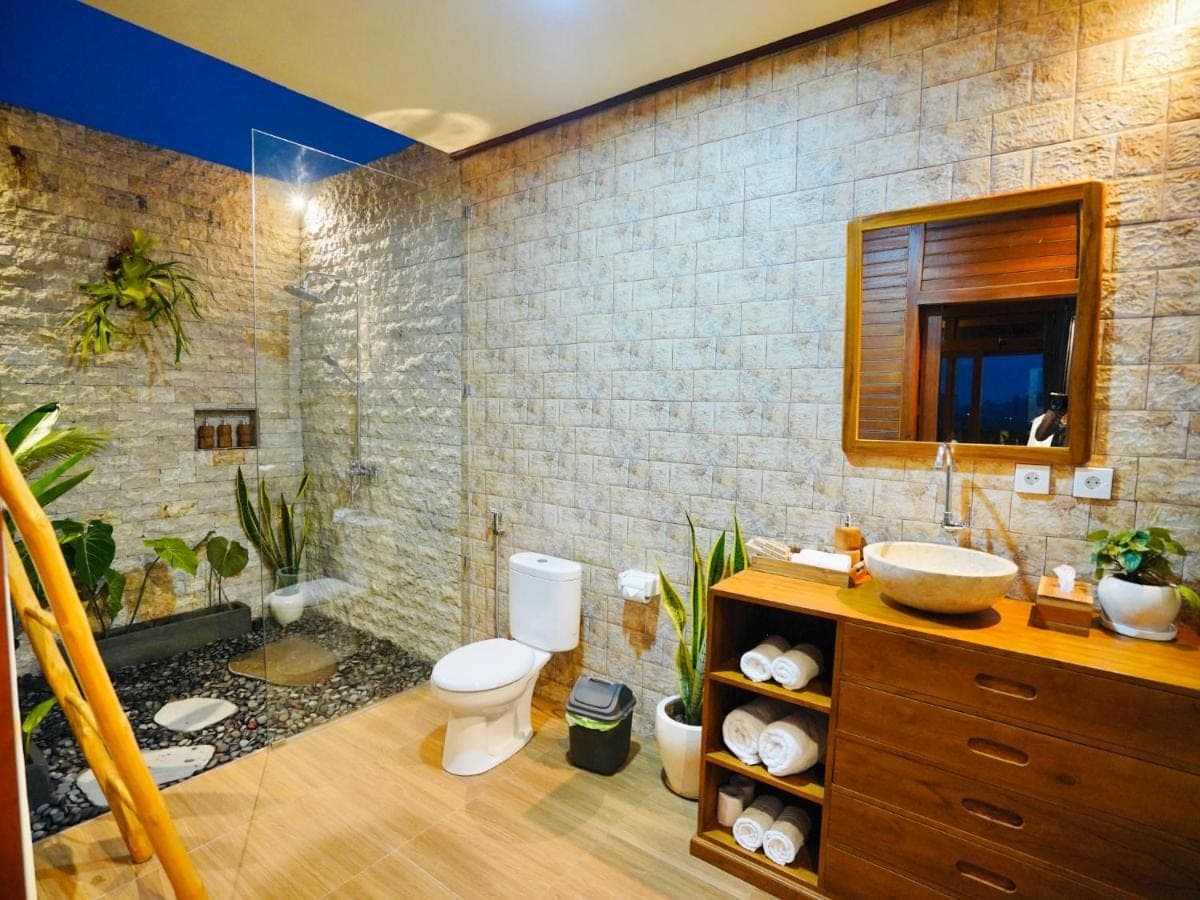 a bathroom with a sink and a toilet and a mirror at Romantic Wooden House with Private Pool in Ubud - Raka d'Uma in Ubud