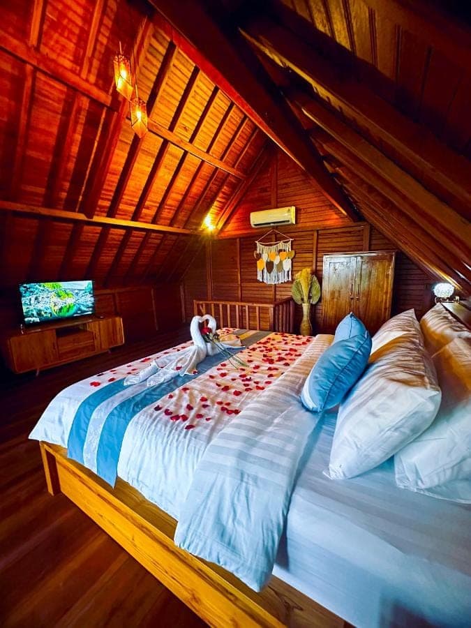 a large bed in a room with a tv at Romantic Wooden House with Private Pool in Ubud - Raka d'Uma in Ubud
