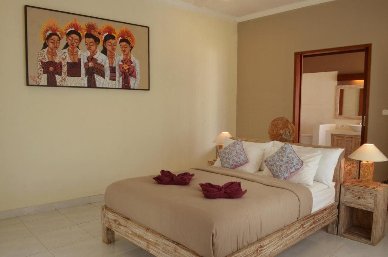 a bedroom with a bed with a picture on the wall at The Bali Shanti in Ubud
