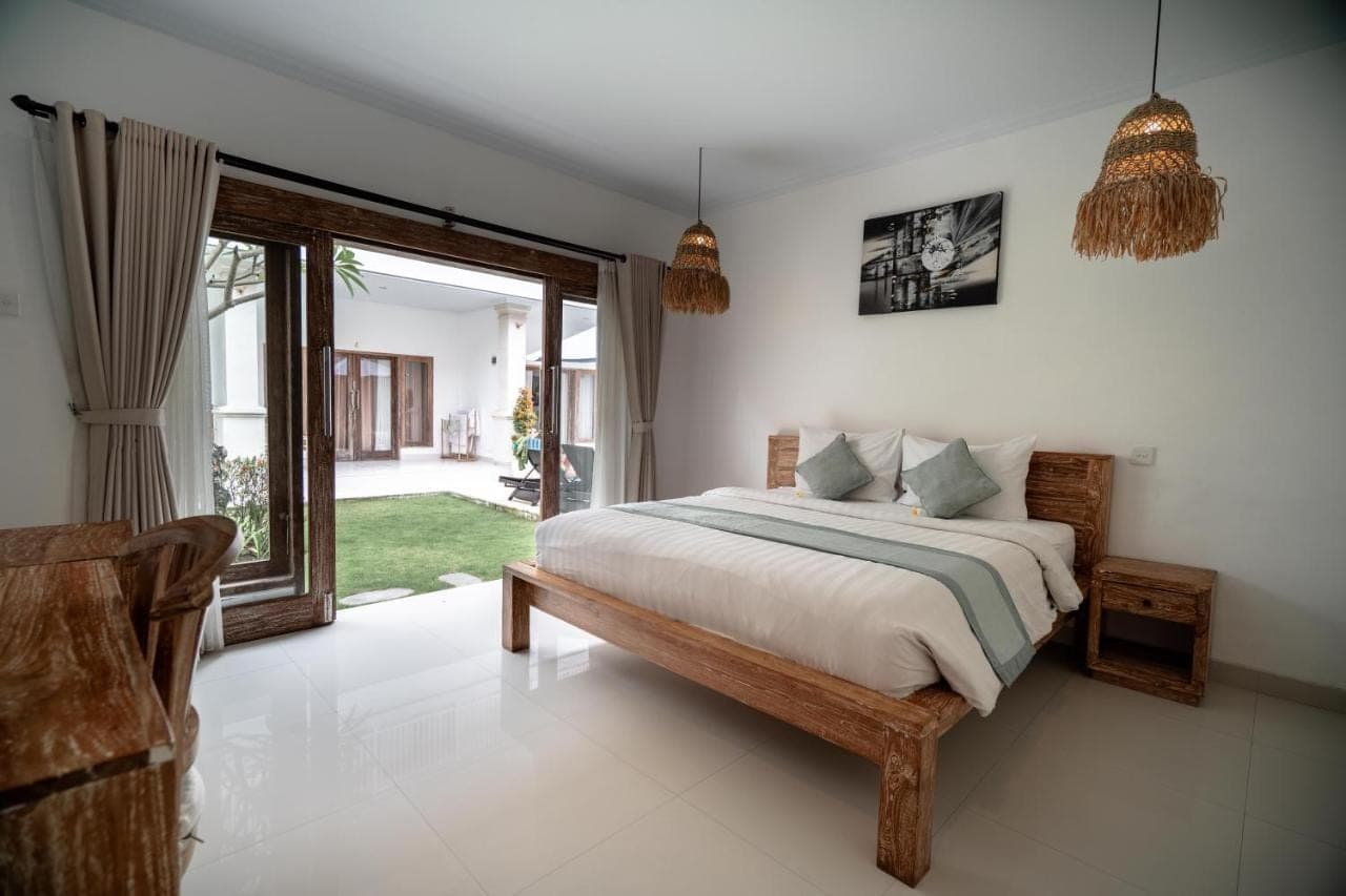 a bedroom with a bed and a sliding glass door at The Eight Villa & Rooms Bali - Seminyak in Seminyak