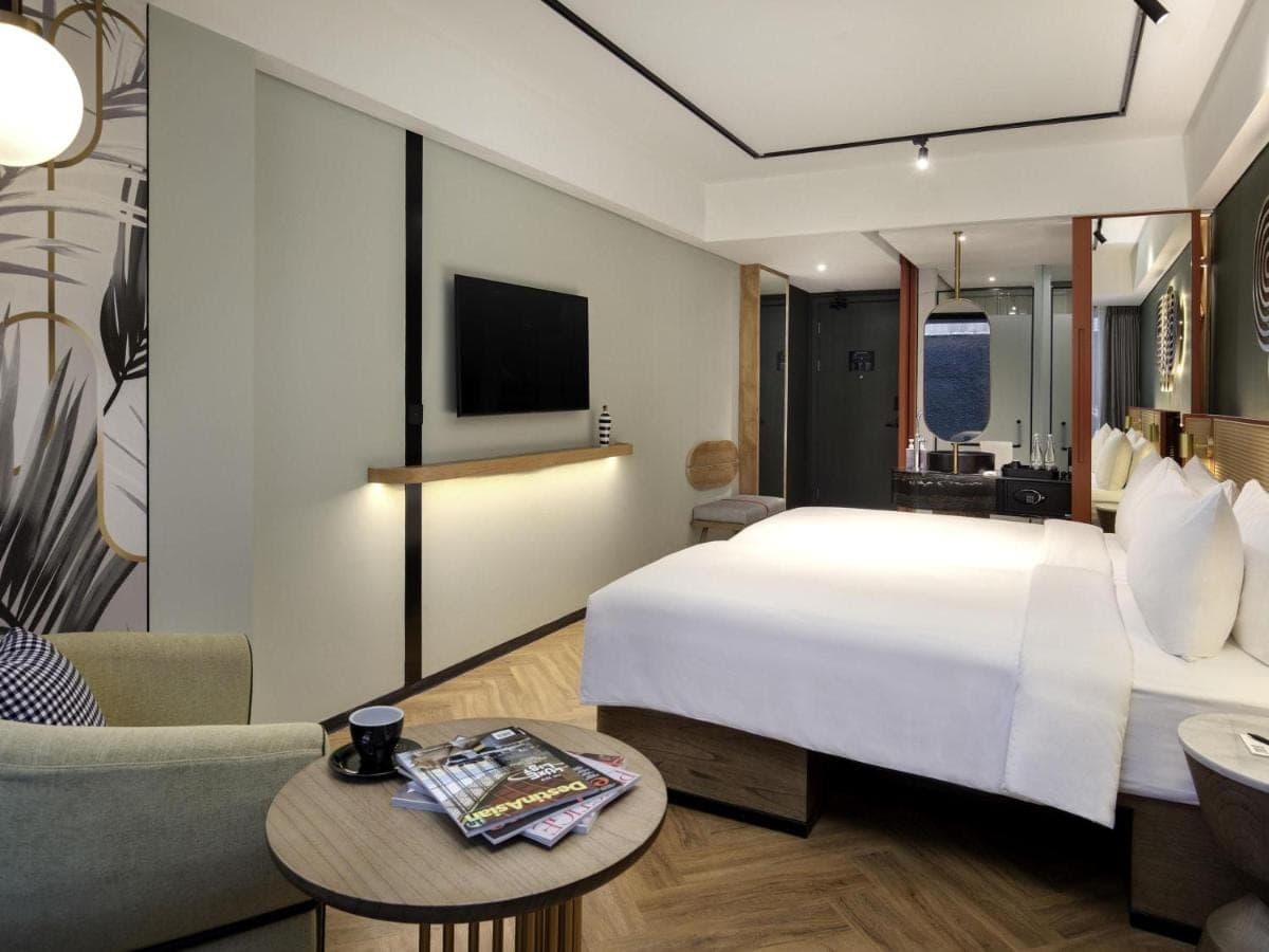 a hotel room with a large bed and a tv at Tribe Bali Kuta Beach in Kuta