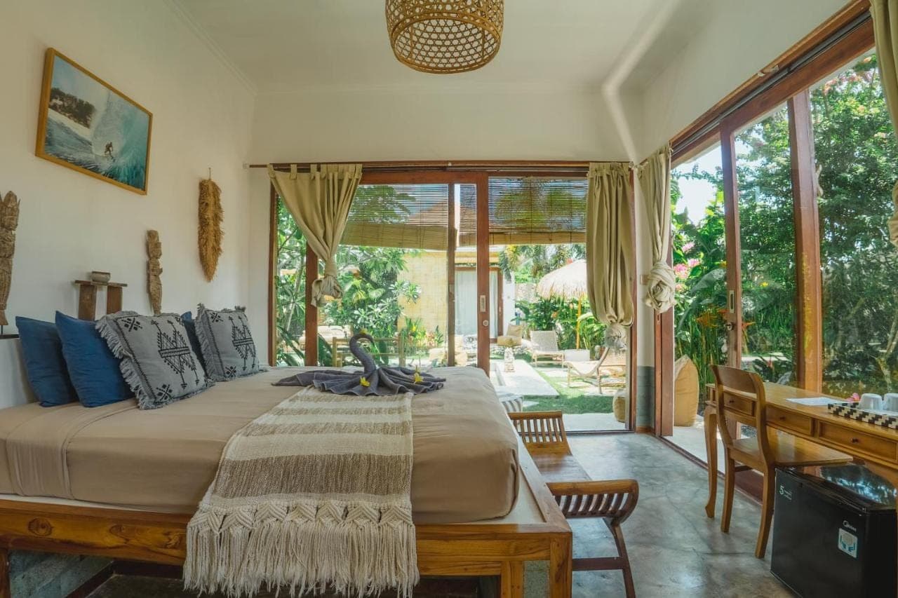 a bedroom with a large bed and a desk and windows at La Kreyiol in Uluwatu