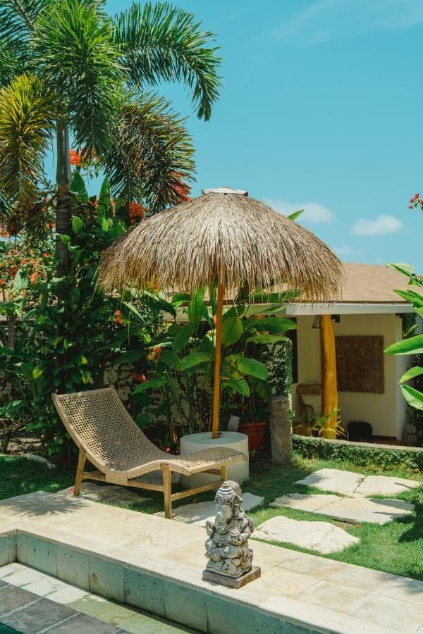 a straw umbrella and a chair under a umbrella at La Kreyiol in Uluwatu