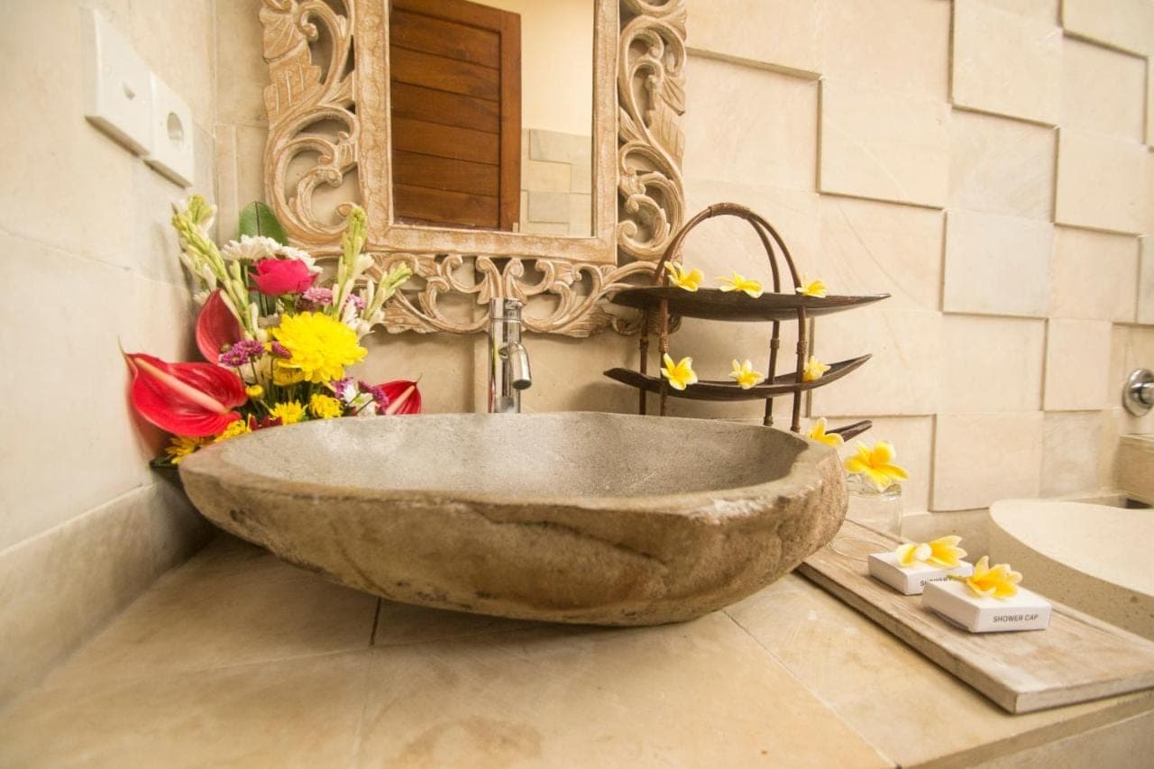 a large stone sink in a bathroom with flowers at Villa Ulun Mertha - 1BR Private Villa in Ubud