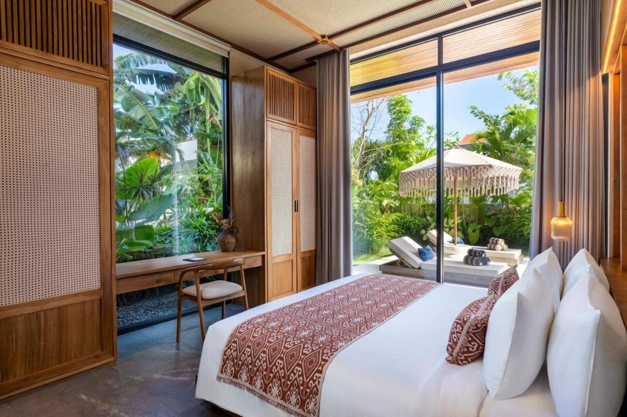 a bedroom with a bed and a desk and a large window at TUI BLUE Berawa Hotel and Villas in Canggu