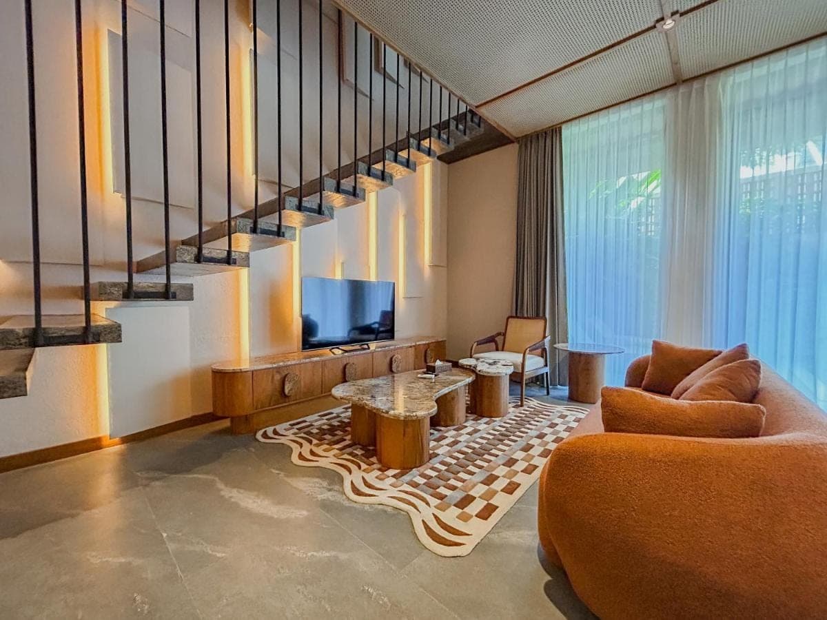 a living room with a couch and a television at TUI BLUE Berawa Hotel and Villas in Canggu
