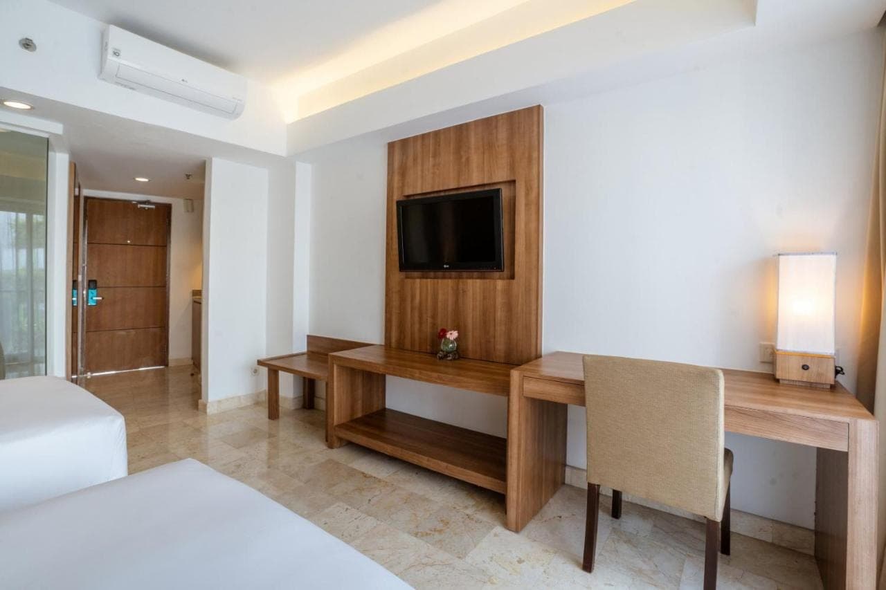 a hotel room with a desk and a television at Cross Vibe Paasha Atelier Bali Kuta in Kuta