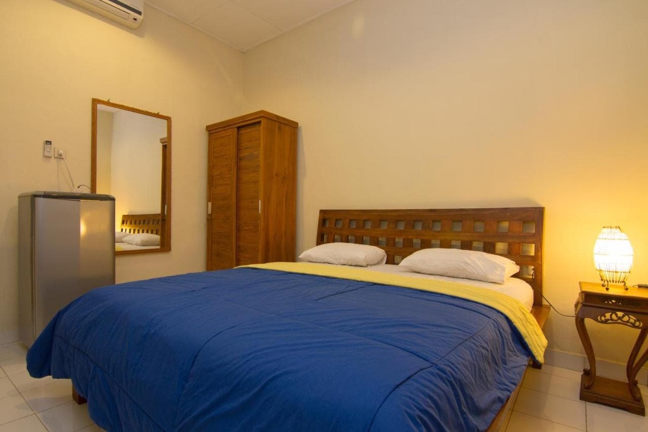 a bedroom with a large bed with a blue blanket at Pondok Nuri Homestay in Sanur