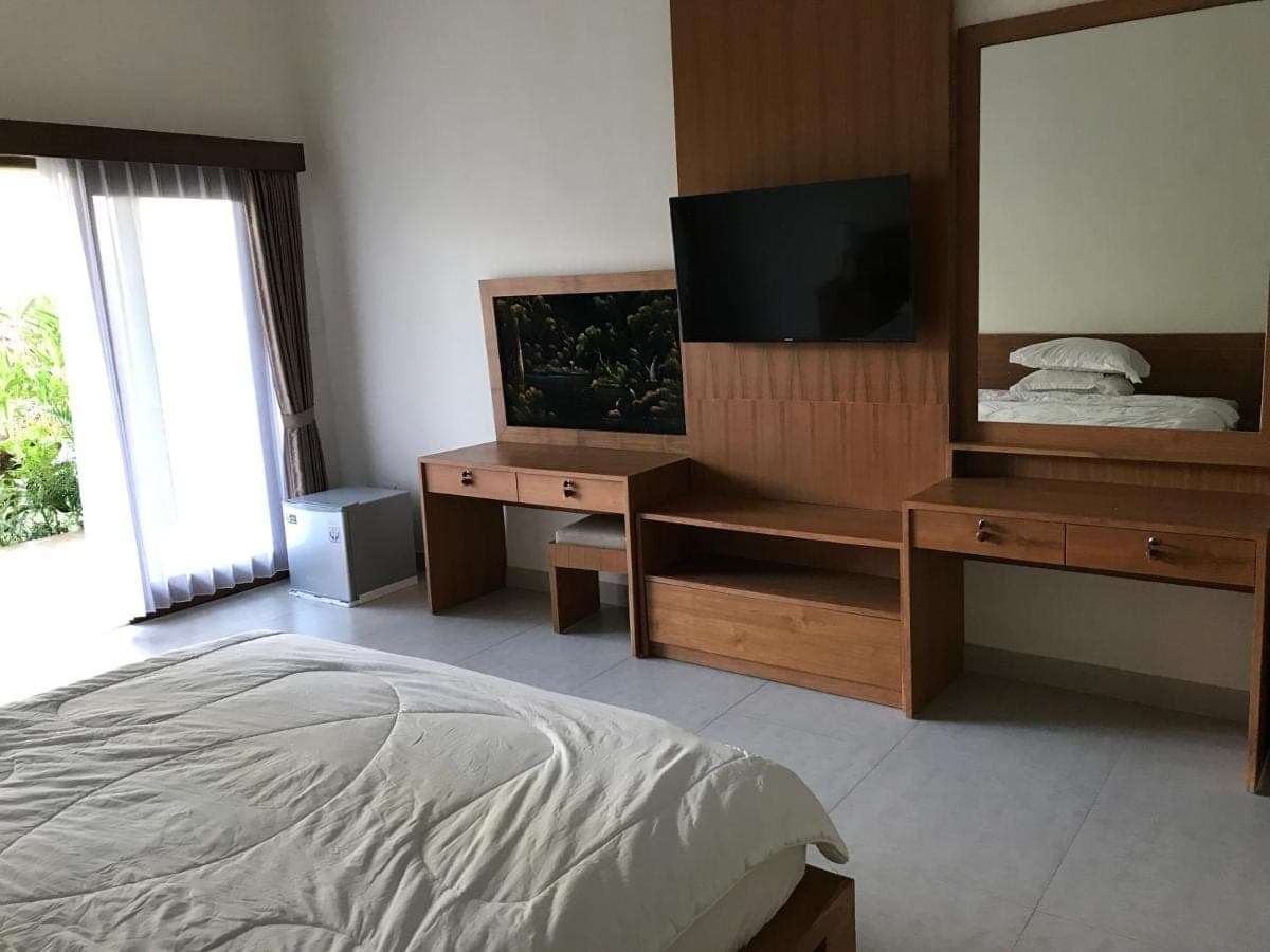 a bedroom with a bed and a dresser and a television at Villa Pulu Uluwatu Bali in Uluwatu