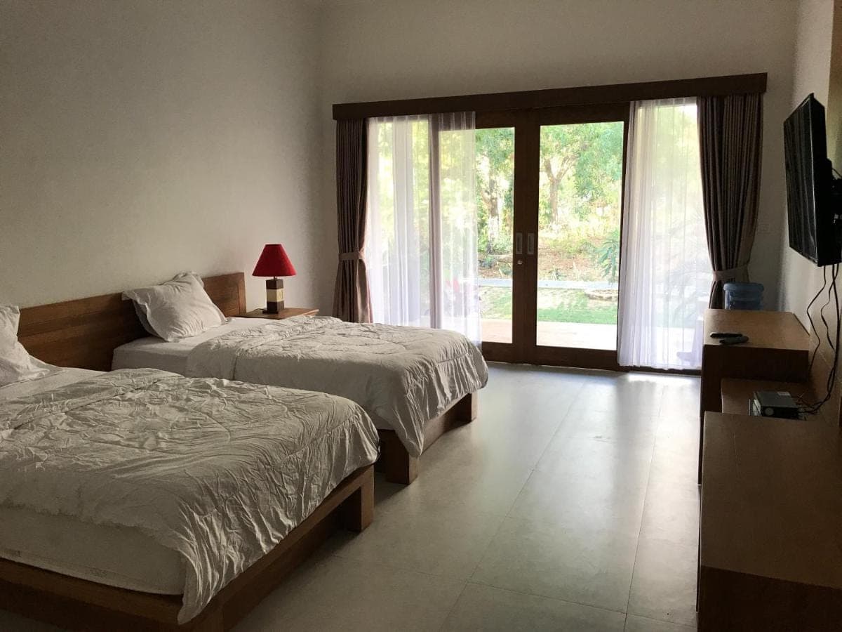 a bedroom with two beds and a sliding glass door at Villa Pulu Uluwatu Bali in Uluwatu