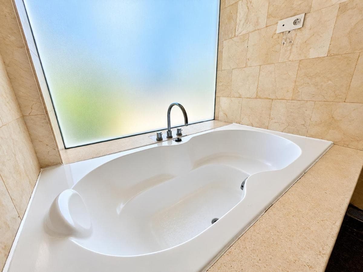 a white tub in a bathroom with a window at The Wangsa Hotel and Villas Nusa Dua in Nusa Dua