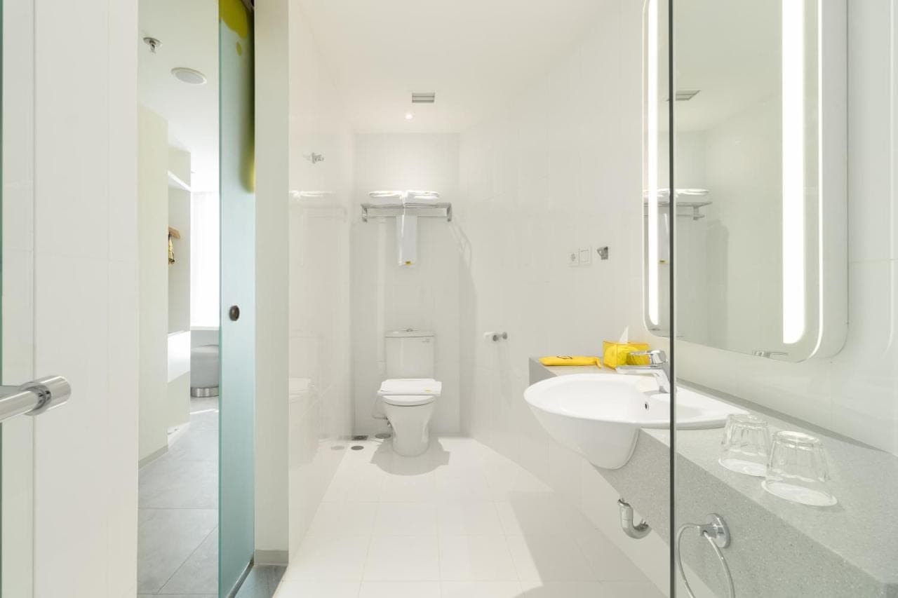 a white bathroom with a toilet and a sink at YELLO Hotel Kuta Beachwalk Bali in Kuta
