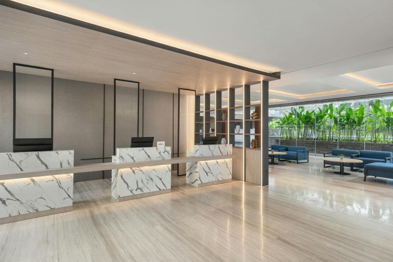 a lobby of a hotel with white chairs and tables at Fairfield by Marriott Bali Kuta Ngurah Rai in Kuta