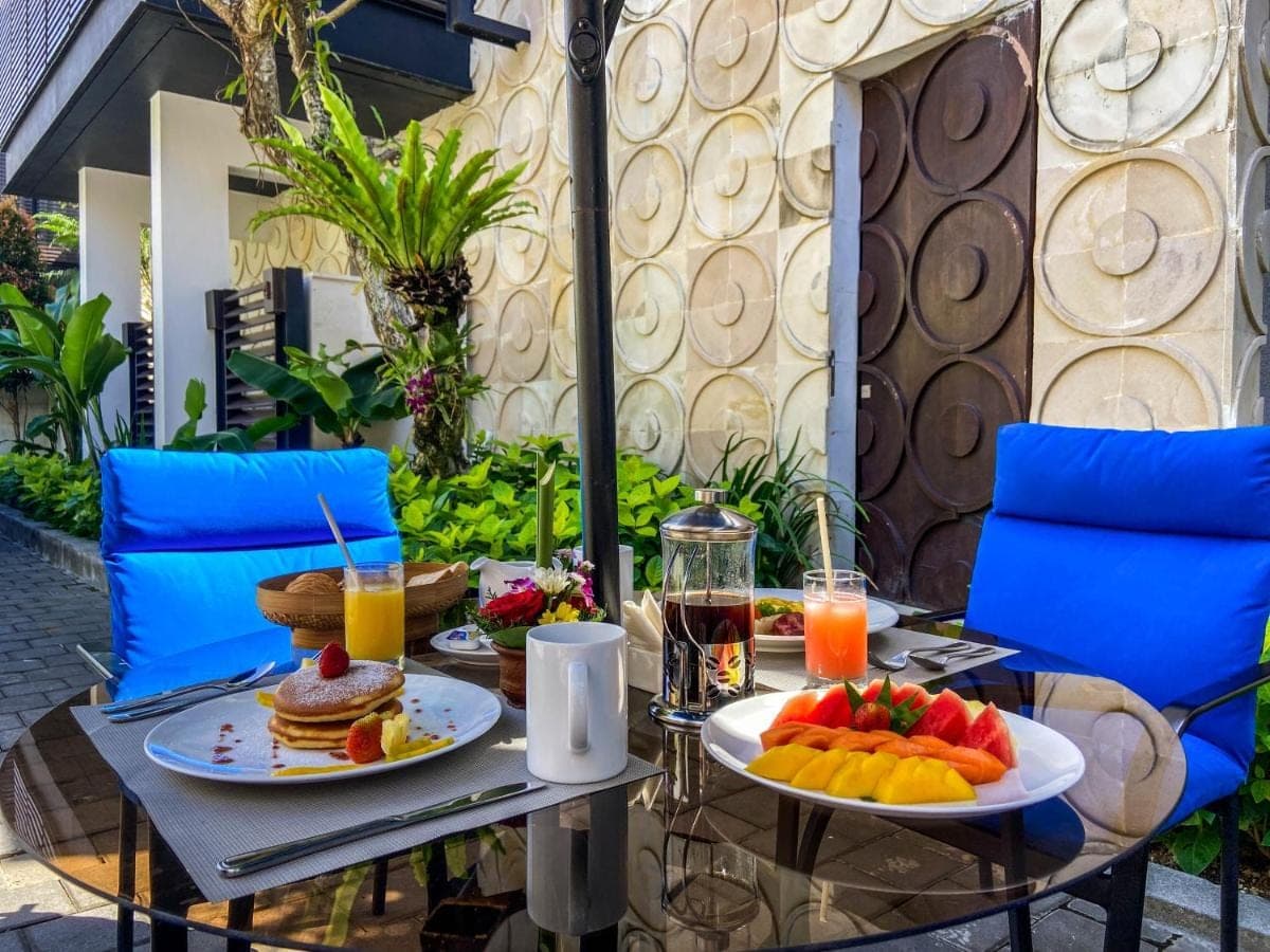 a table with two plates of food and fruit on it at Puri Hiromi Boutique Residence in Sanur