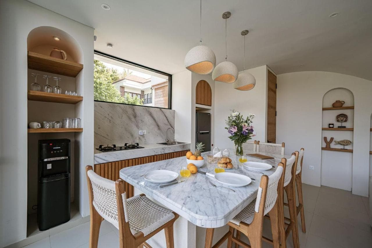 a dining room with a table and chairs and a kitchen at Villa Good Juju Uluwatu in Uluwatu
