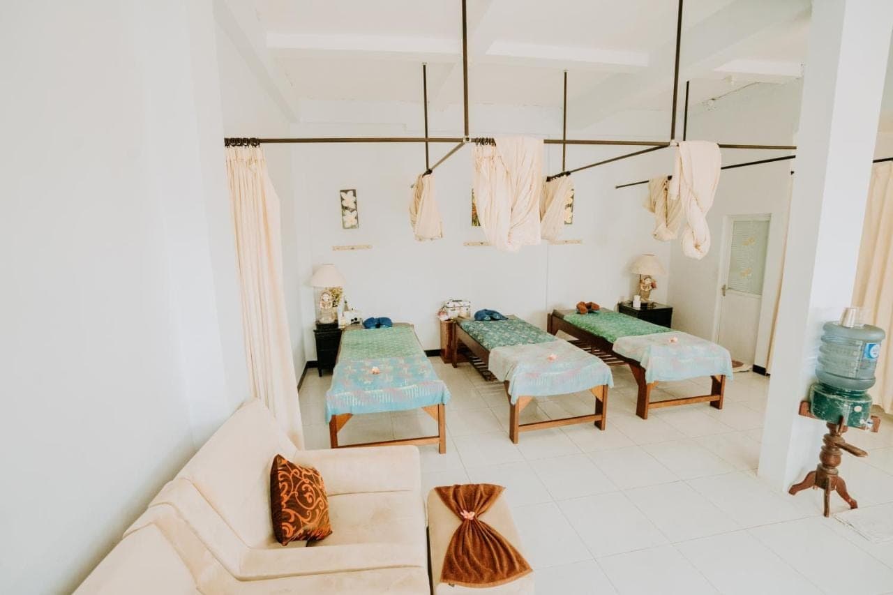 a living room with couches and chairs and a chandelier at Nova Guest House in Canggu