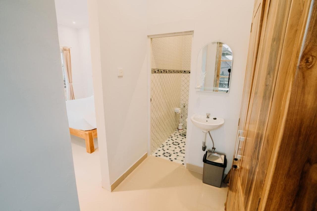 a white bathroom with a sink and a shower at Nova Guest House in Canggu