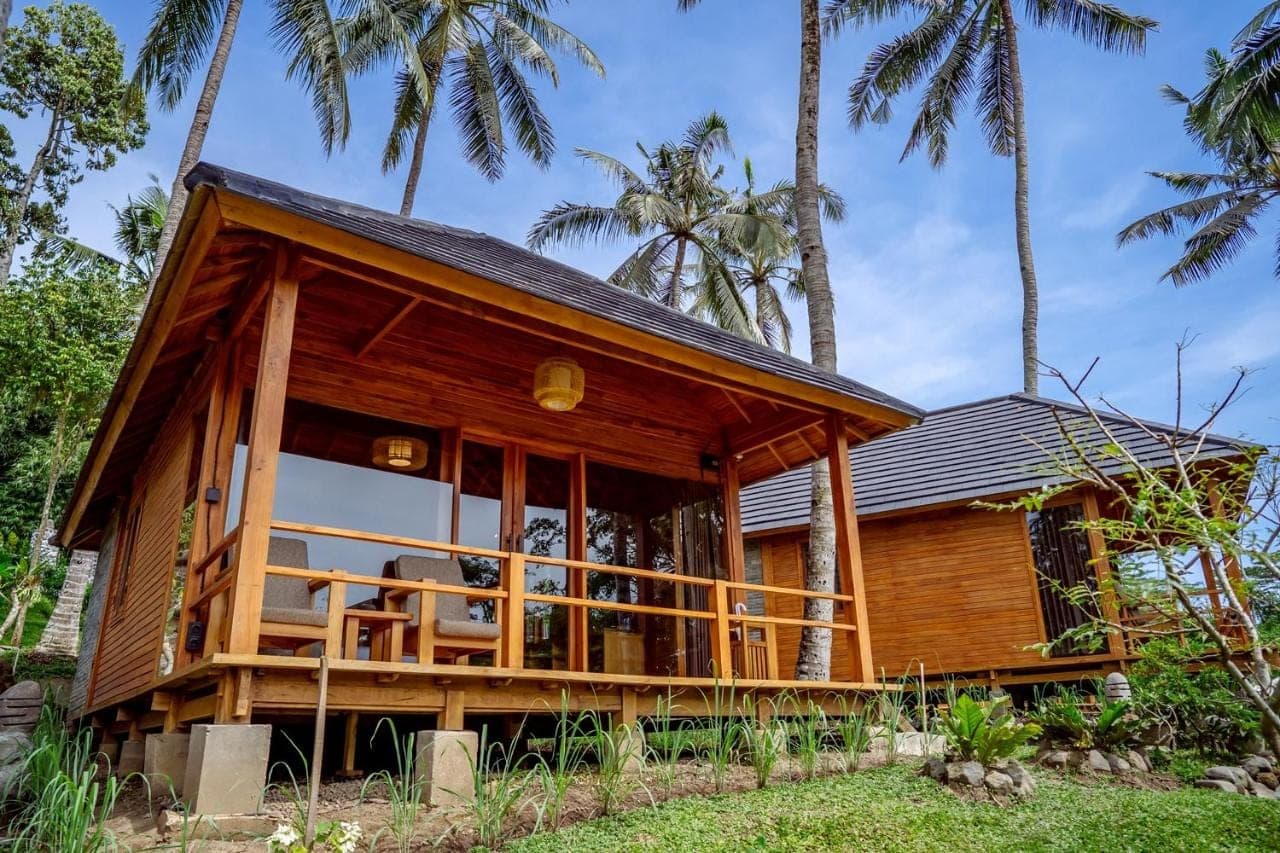 a house on the beach with palm trees at Taman Swarga Villa Resort & Spa Sidemen in Sidemen