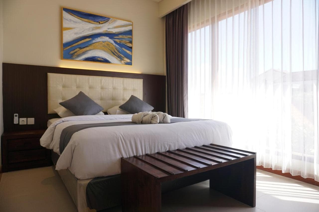 a bedroom with a large bed and a window at Taman Agung Hotel in Sanur