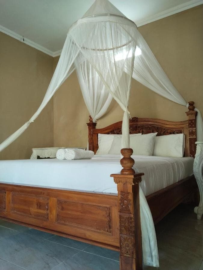 a bedroom with a canopy bed with white drapes at Khailash Warung and Home Stay in Sidemen