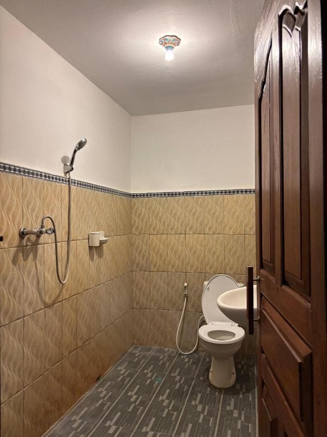 a bathroom with a toilet and a shower in it at Khailash Warung and Home Stay in Sidemen