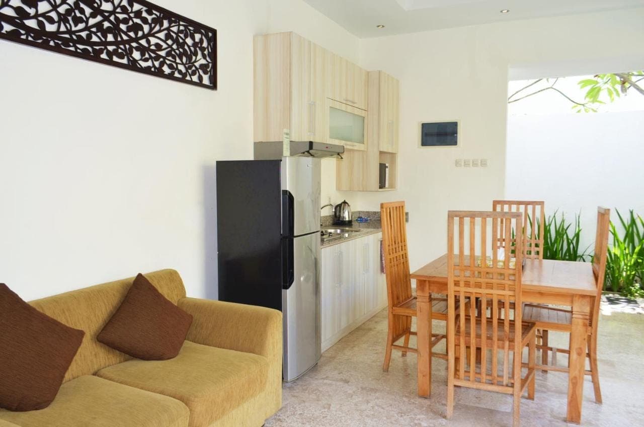 a living room with a couch and a table and a kitchen at Jas Green Villas and Spa in Seminyak