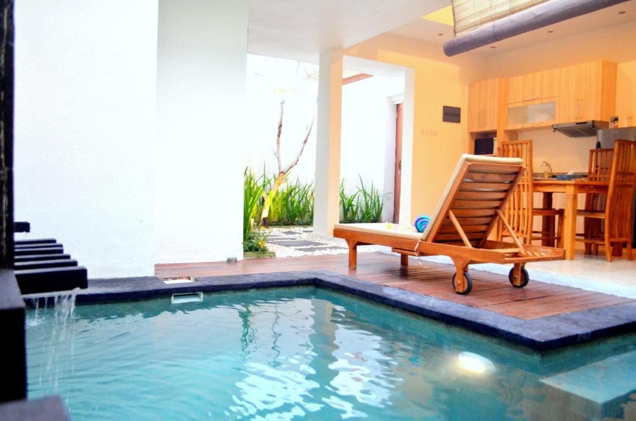a chair sitting next to a swimming pool at Jas Green Villas and Spa in Seminyak