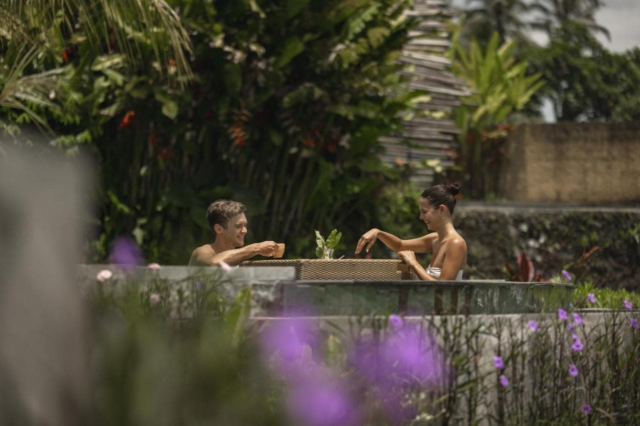 two men sitting in a bathtub in a garden at Beehouse Dijiwa Ubud in Ubud