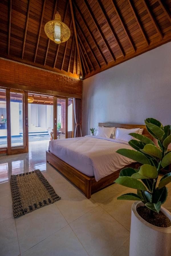 a bedroom with a bed and a potted plant at Askay Homestay Uluwatu in Uluwatu